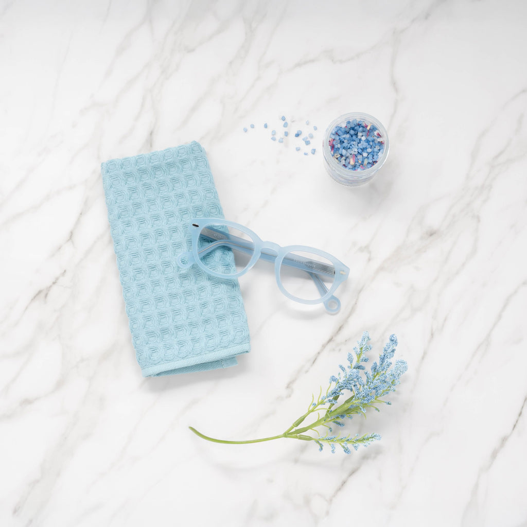 Pastel Blue Showerspecs reading glasses on a bathroom countertop.