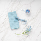 Pastel Blue Showerspecs reading glasses on a bathroom countertop.