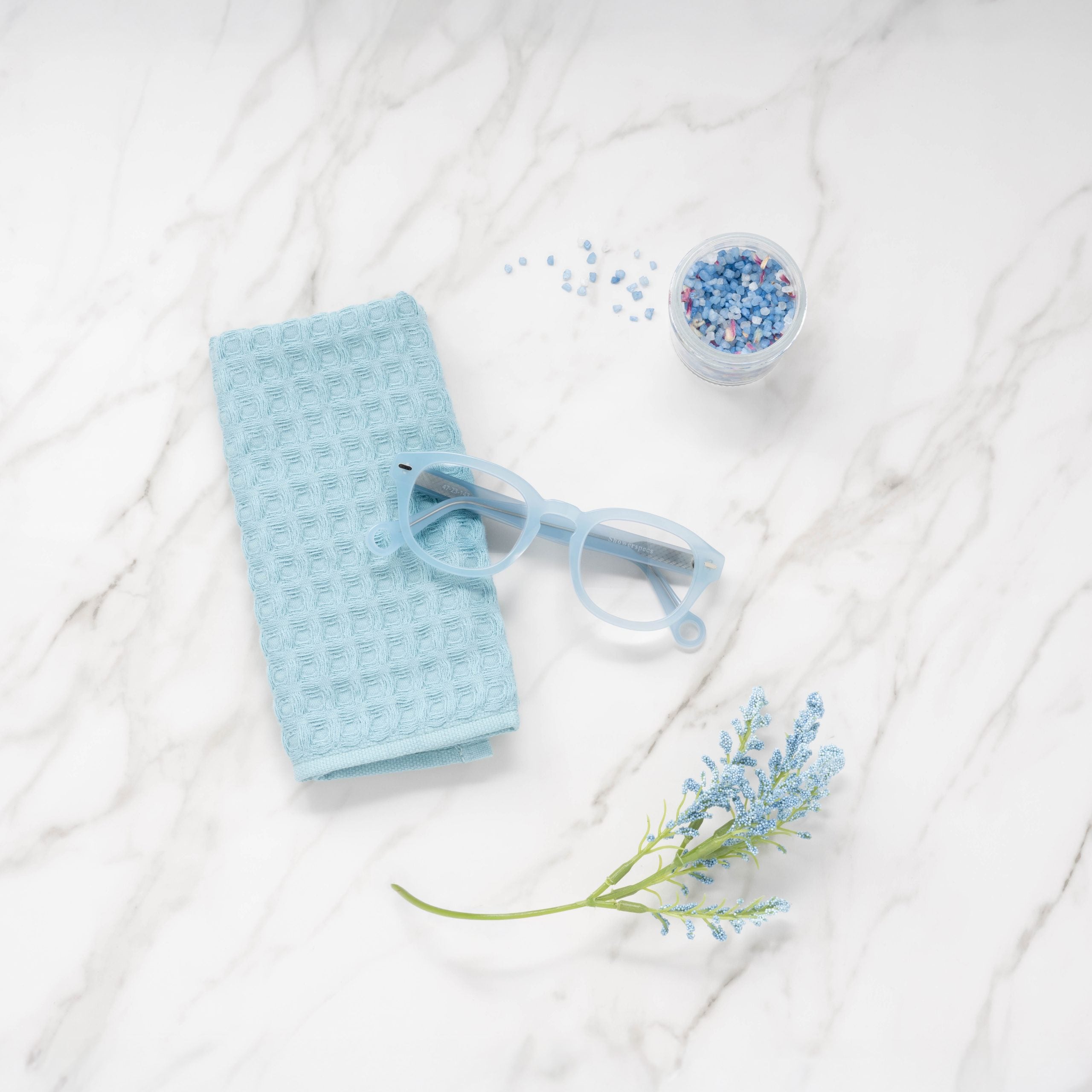Pastel Blue Showerspecs reading glasses on a bathroom countertop.
