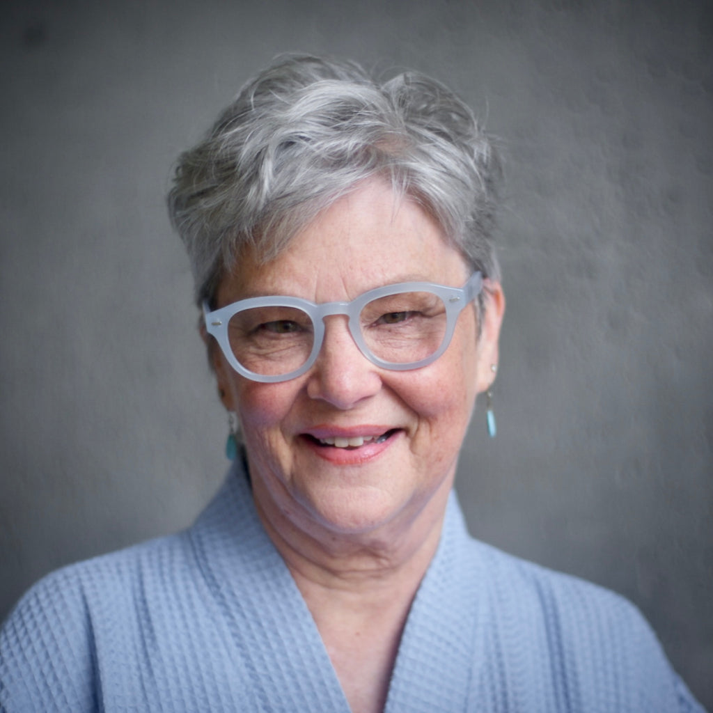 A woman wearing Pastel Blue Showerspecs reading glasses.