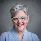 A woman wearing Pastel Blue Showerspecs reading glasses.