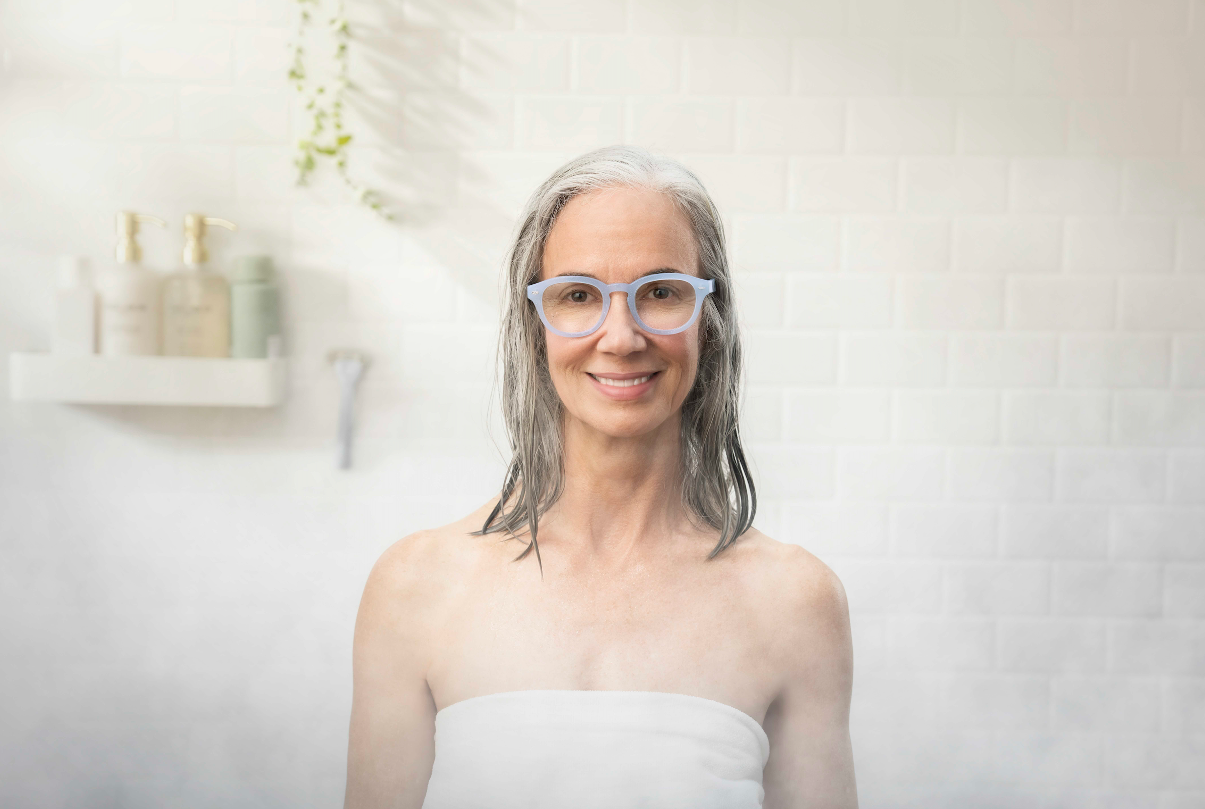 Woman wearing blue Showerspecs reading glasses in the shower.