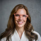 Woman wearing Warm Coral Showerspecs and a bathrobe. 