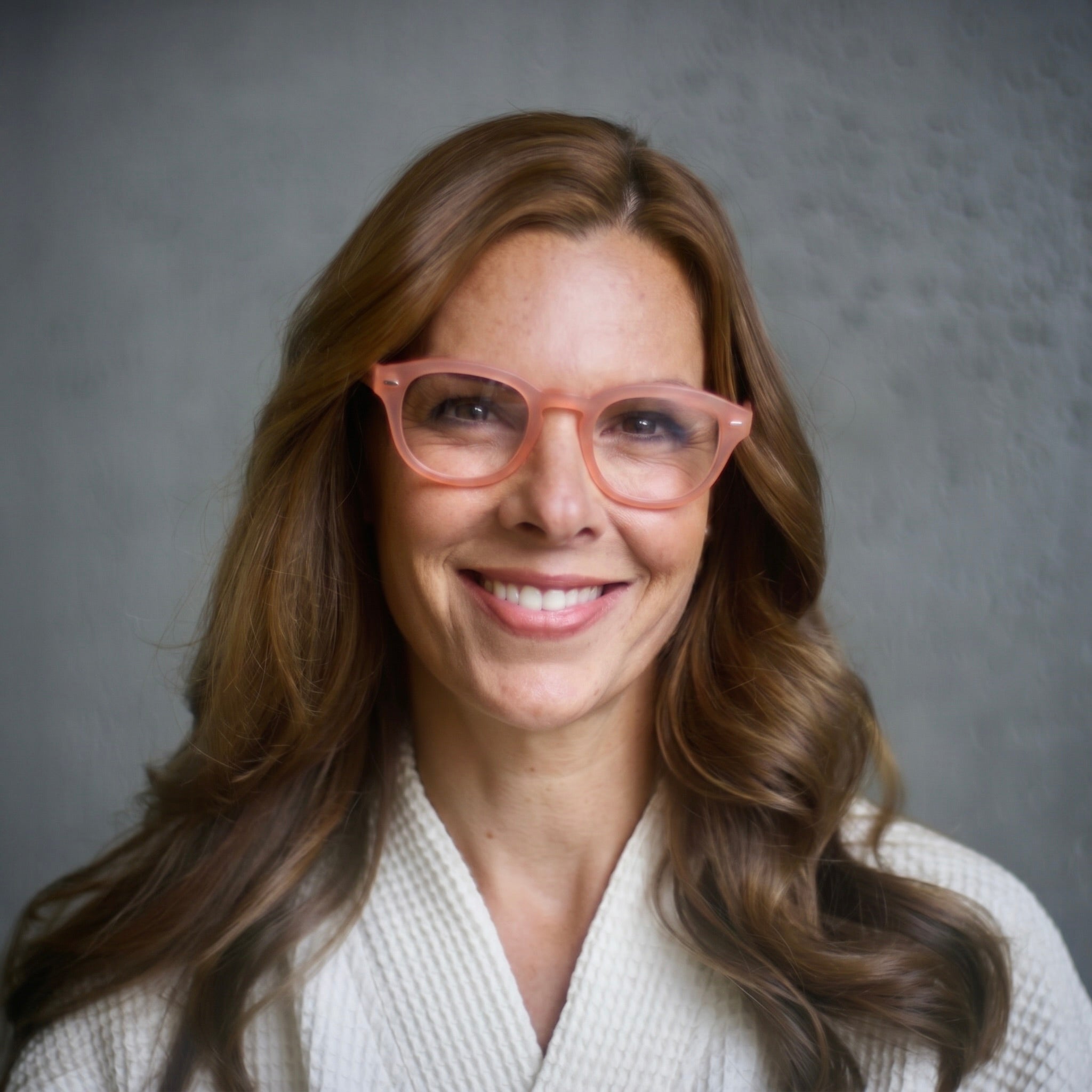 Woman wearing Warm Coral Showerspecs and a bathrobe. 