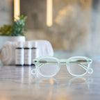 Misty Green Showerspecs reading glasses on a bathroom countertop.