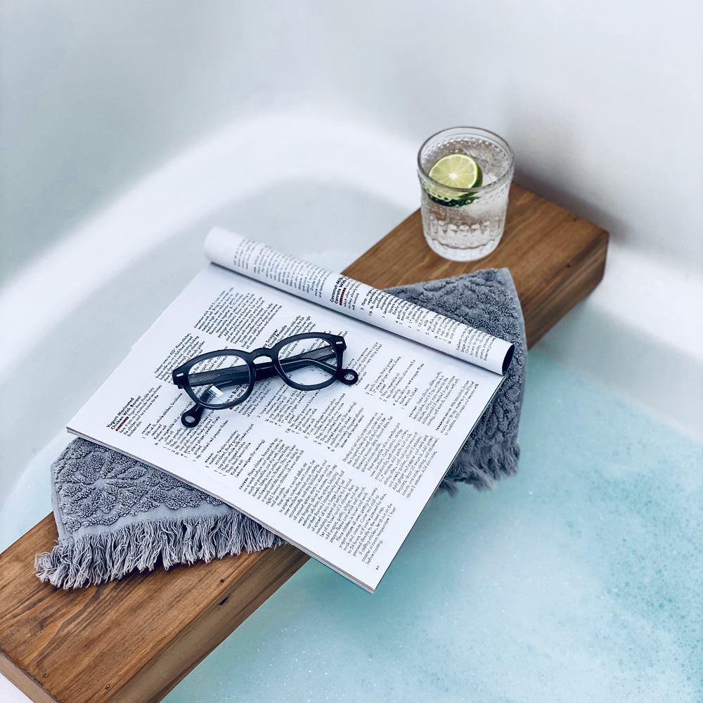 Showerspecs anti-fog glasses on an open magazine beside a bathtub.