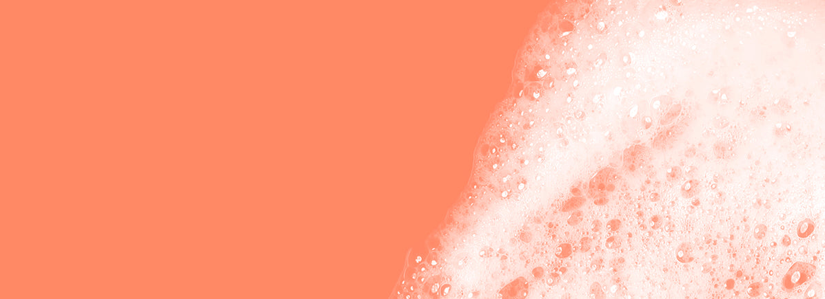 Close-up of soap bubbles on a coral background.