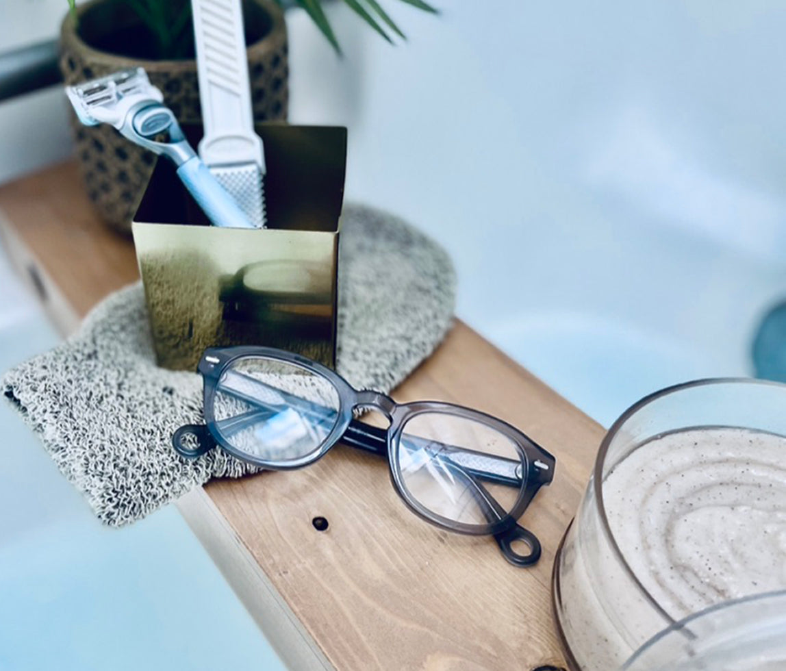 Stone Gray Showerspecs reading glasses on a towel beside a bathtub.